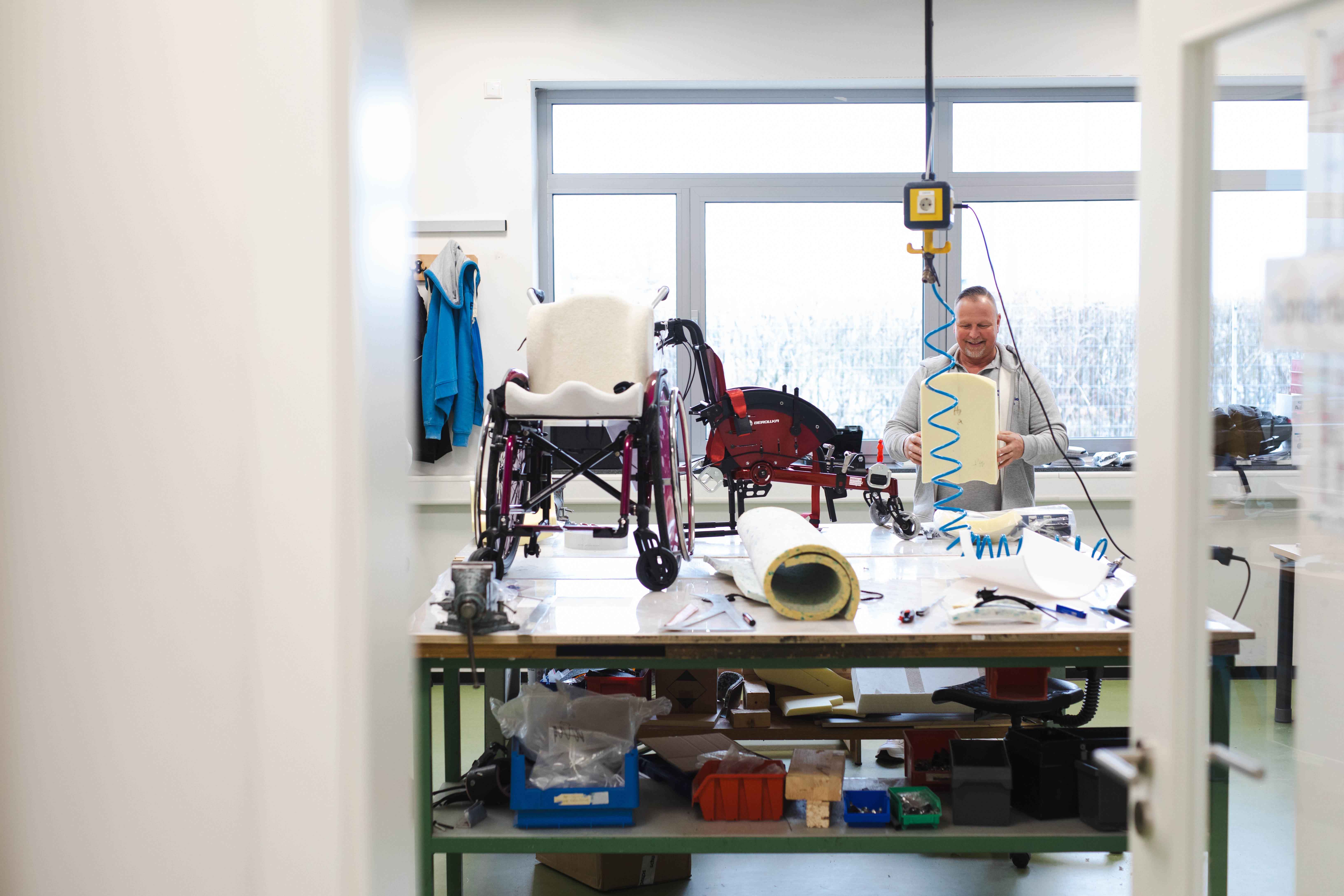 Ein Blick in die reha-Sonderbau-Werkstatt von hodey kids. Im Hintergrund arbeitet Bernd von Hodey Kids an einem Hilfsmittel.